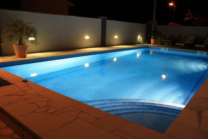 Beleuchteter Pool mit Einladung zum Nachtschwimmen bildet eine herrliche Kulisse an den warmen spanischen Abenden.