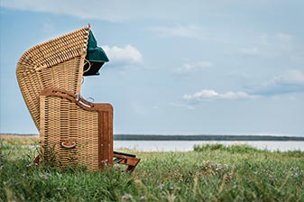 Strandkorb auf einer Grasfläche am Meer
